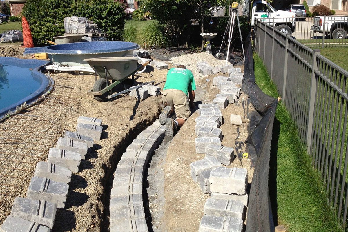0_0003_landscape Worker laying bricks near a pool.