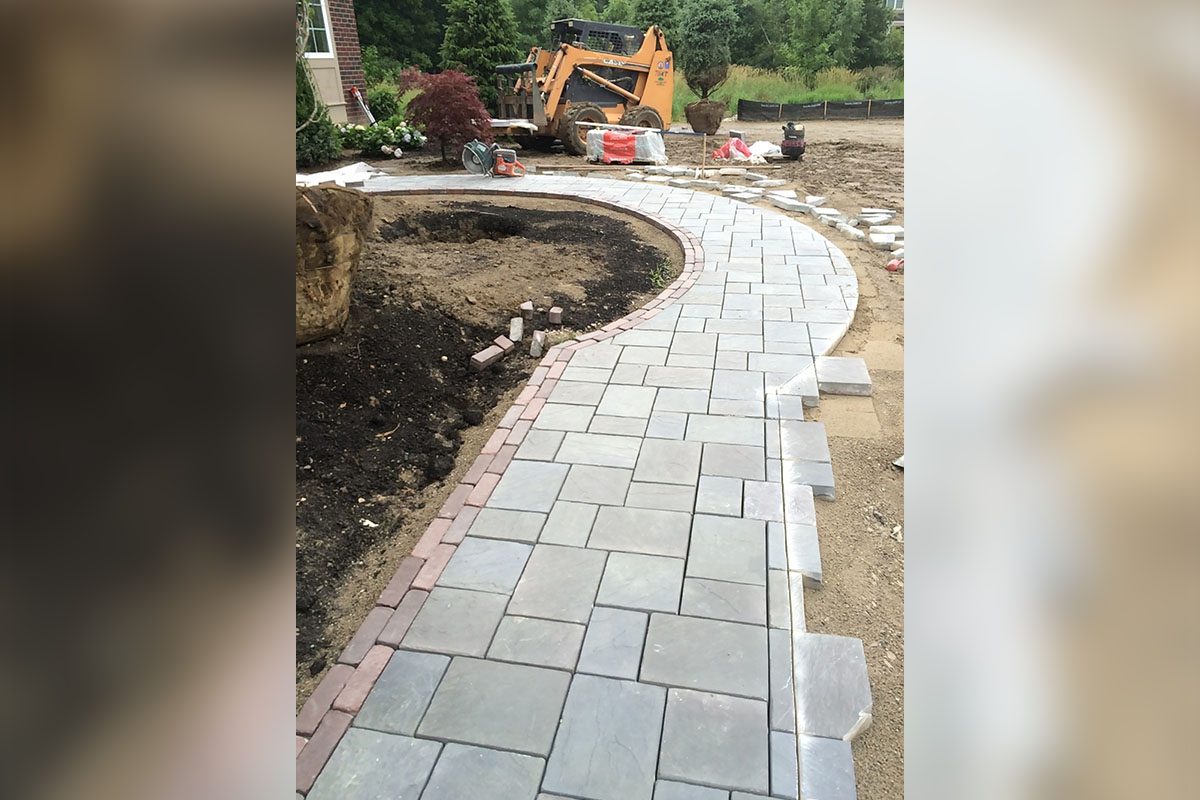 Curved stone pathway with construction equipment nearby.