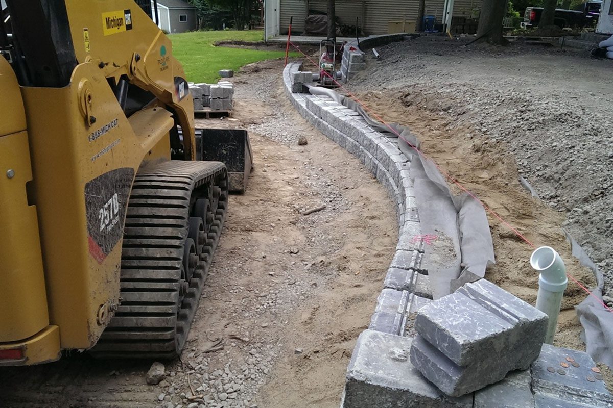 Construction site with excavator and stone wall.