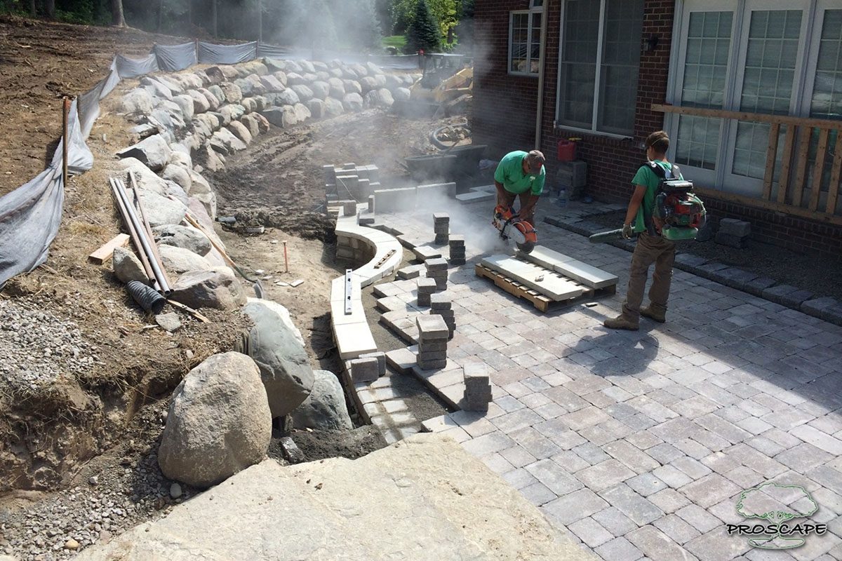 Landscapers constructing stone retaining wall.