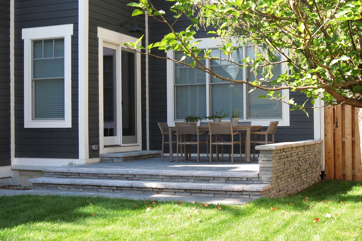 Patio with table and chairs, tree nearby.