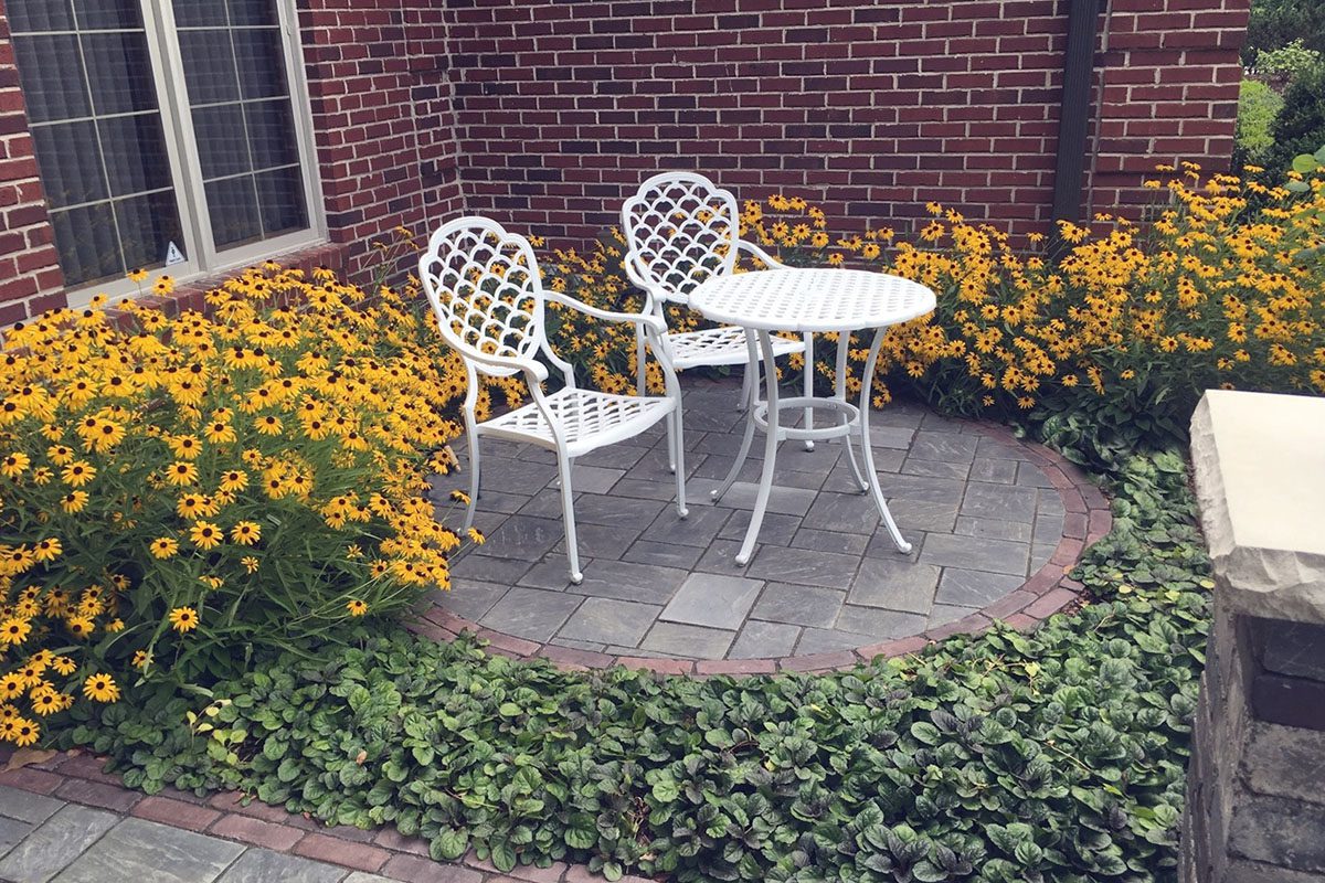 White patio set amidst yellow flowers.