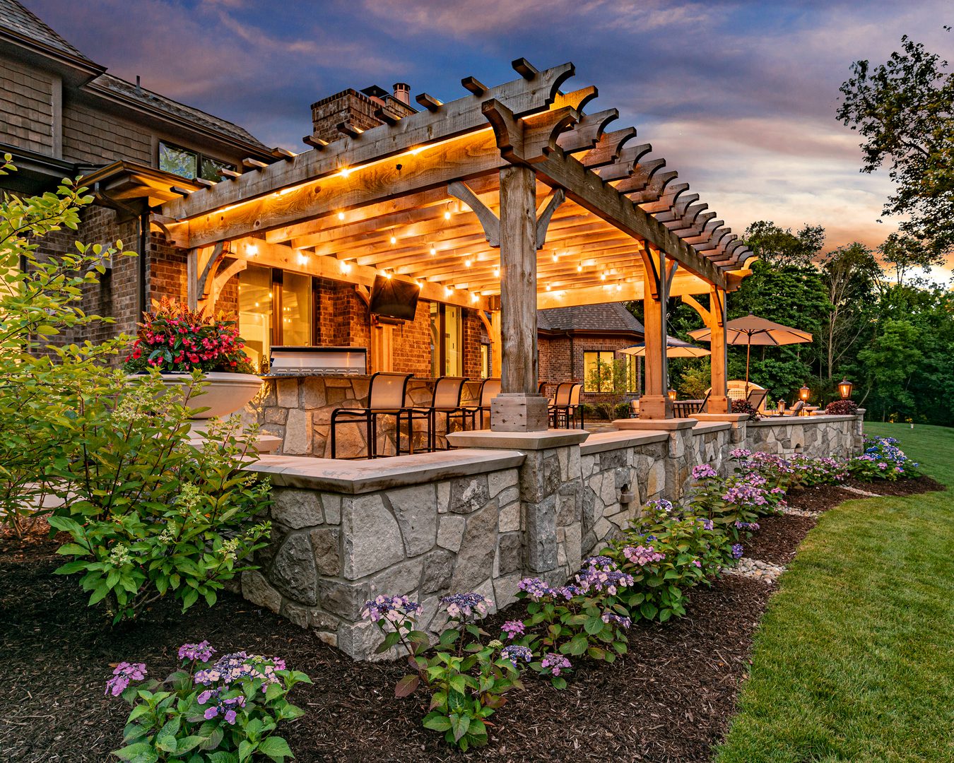 gold-1 Illuminated patio with pergola and seating area.