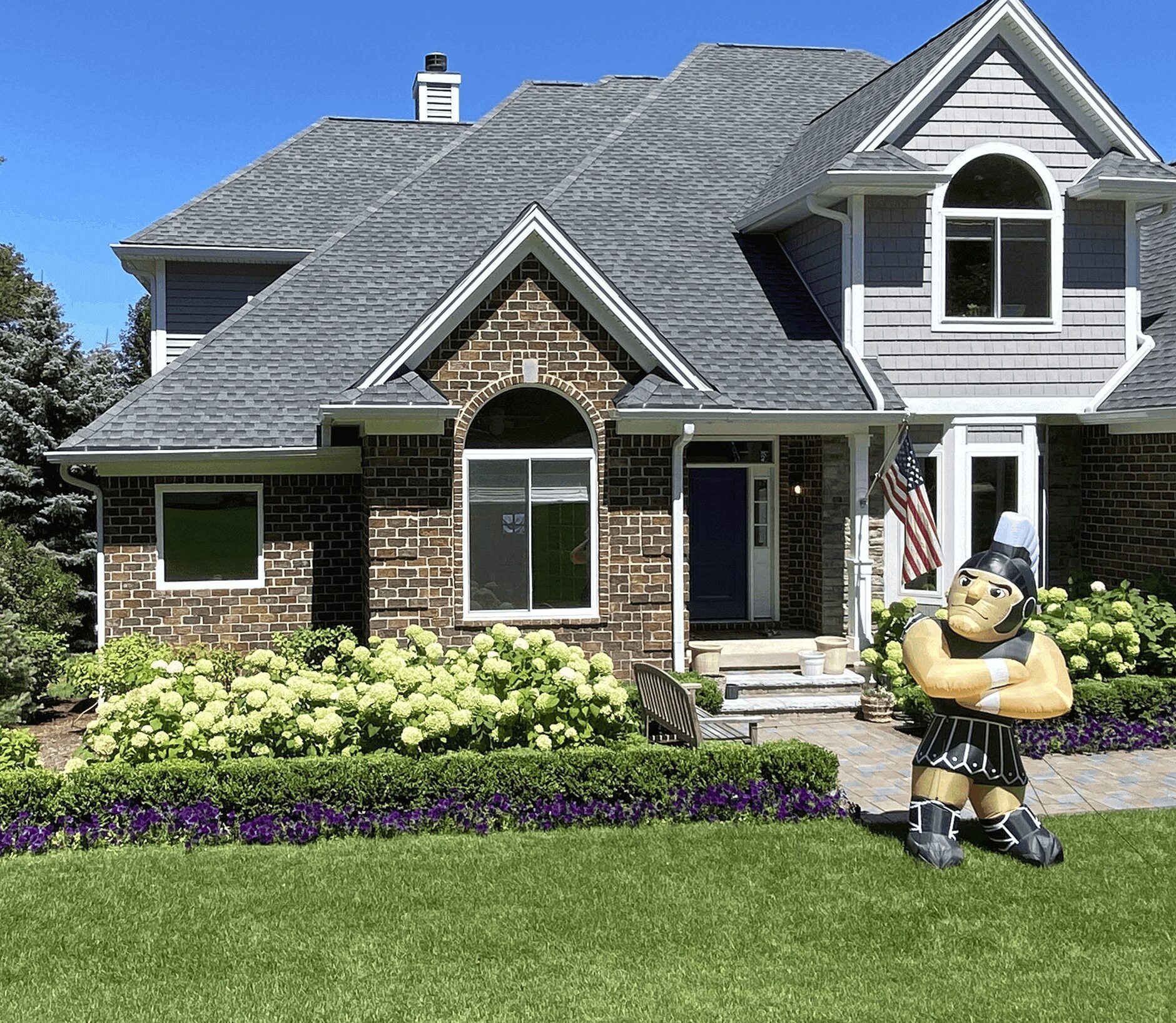 iop (1) (1) House with garden and large cartoon statue.