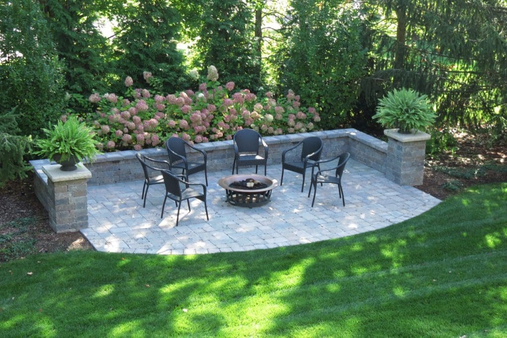Patio with chairs, fire pit, and plants.