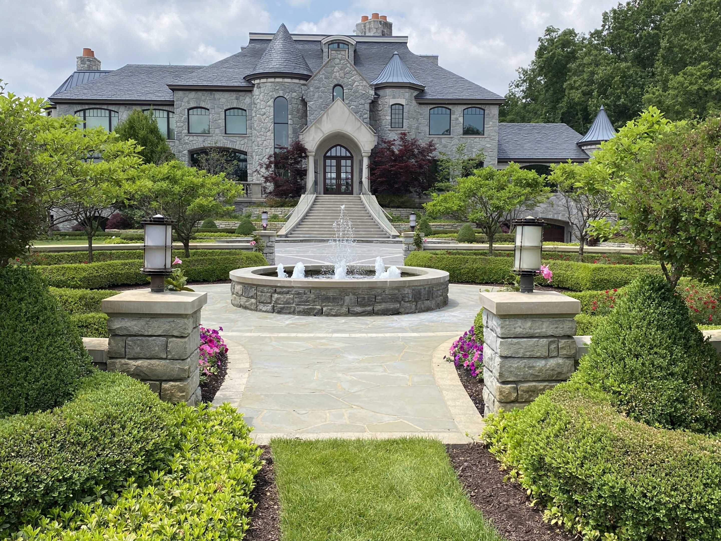 A large garden with a fountain and a house.