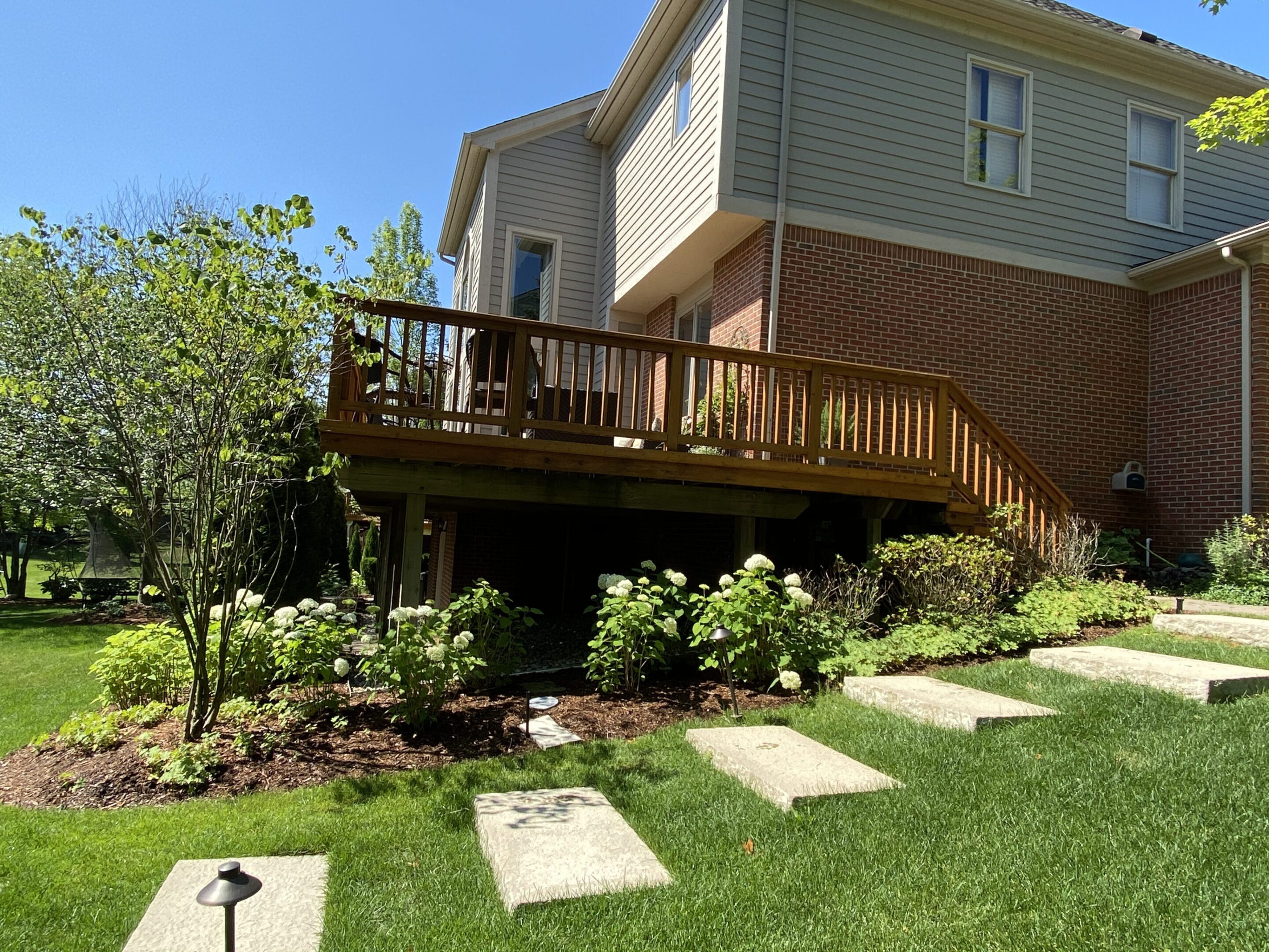 A house with a deck and lawn in it