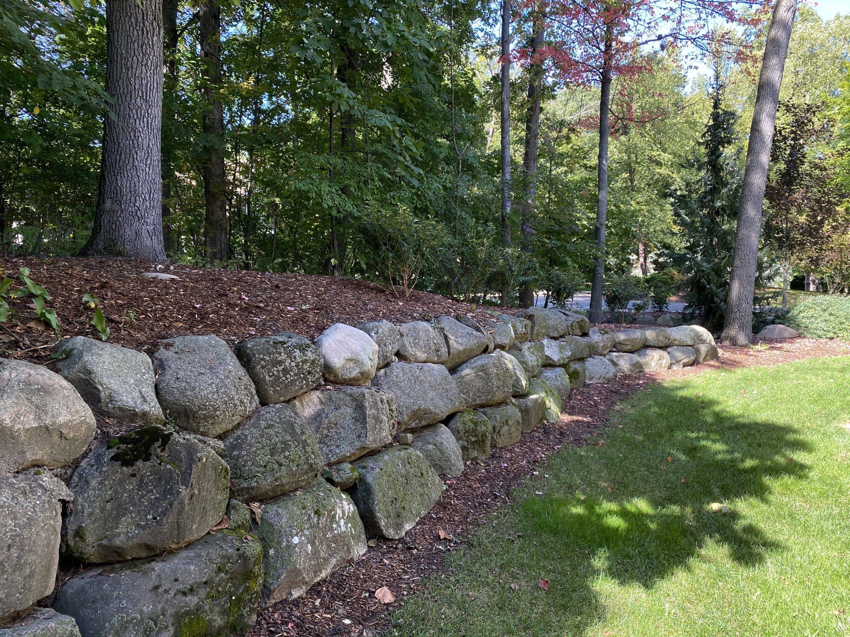 A stone wall in the middle of a yard.